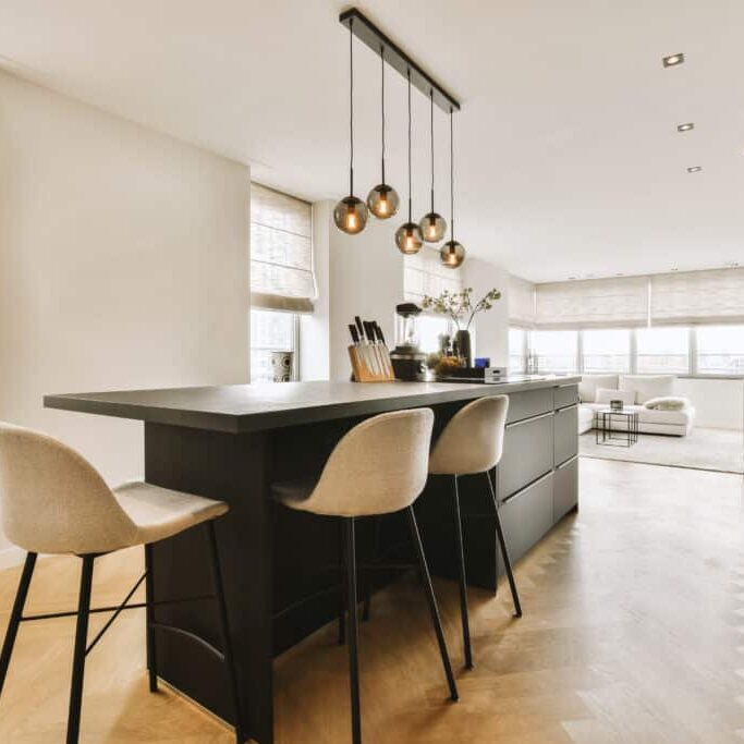 a kitchen with a black island and three stools